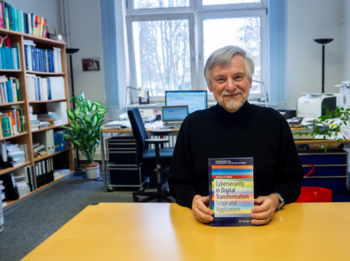 Person sitzt auf einem Schreibtisch und hält ein Buch 